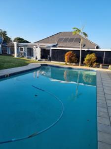 a swimming pool with blue water in front of a house at Troon Harmony - Room 3 in Durban
