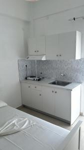 a white kitchen with a sink and a counter at Mimika studios in Pefki +7 photos