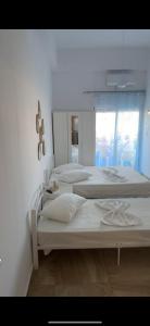 two white beds in a room with a window at Mimika studios in Pefki
