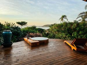 a wooden deck with a table and chairs on it at Fazenda do Rosa in Praia do Rosa
