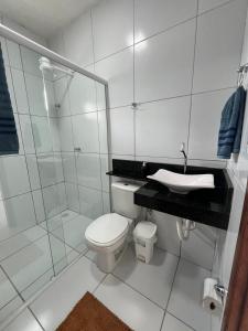 a white bathroom with a toilet and a sink at Casa para o Natal perto do palco centro, 3 quarto in Garanhuns