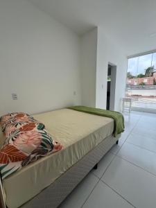 a bed in a white room with a large window at Casa para o Natal perto do palco centro, 3 quarto in Garanhuns