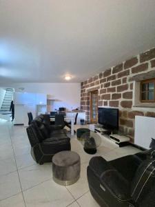 a living room with black furniture and a stone wall at Chambres d'hôtes - La correziene in Allassac
