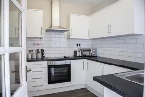 a kitchen with white cabinets and a black counter top at Spacious House 10min to Liverpool Centre in Wallasey