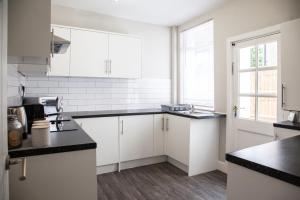 a kitchen with white cabinets and black counter tops at Spacious House 10min to Liverpool Centre in Wallasey +49 photos