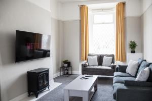 a living room with a couch and a tv at Spacious House 10min to Liverpool Centre in Wallasey