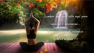 a woman doing a yoga pose in front of a waterfall at Casa Praia e Piscina in São Francisco do Sul