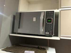 a microwave oven sitting on a shelf in a kitchen at Flat Hotel morador 1110 Suíte,Sofá,Varanda,Cozinha in Nova Iguaçu