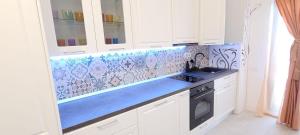 a kitchen with white cabinets and a blue counter top at Apartament Carmen Studio in Eforie Nord