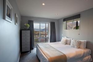 1 dormitorio con 1 cama grande y balcón en Highview Terrace by Amazing Accom, en Queenstown