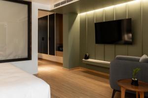 a room with a bed and a tv and a couch at Spektrum Hotel - Bengaluru Airport in Bengaluru