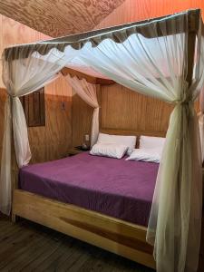 a bedroom with a canopy bed with purple sheets at Finca las Isabeles in Xochitepec