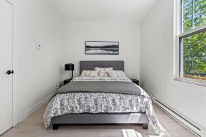 a white bedroom with a bed and a window at Appartement haut de gamme NDG in Montreal