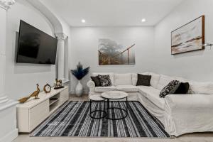 a living room with a white couch and a tv at Appartement haut de gamme NDG in Montreal
