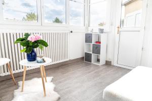 a room with a table with a vase of flowers on it at 5 min château Charmante maison et son jardin privé in Versailles +11 photos