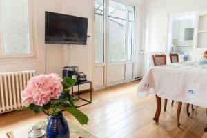 a living room with a table and a vase with a flower at 5 min château Charmante maison et son jardin privé in Versailles