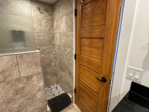 baño con ducha y puerta de madera en Luxury Oceanfront Turtles Sunsets - indigomaui -, en Kahana