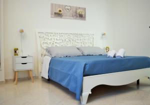 una camera bianca con un letto con una coperta blu di Villa Rosi a Isola delle Femmine
