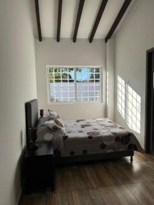 a bedroom with a bed and two windows at Hermosa cabaña en Guarne in Copacabana