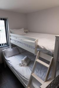 a bedroom with two bunk beds with white sheets at Pierside Apartments Deluxe Accommodation in Portsalon