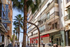 a street with a palm tree in front of a building at Apartment Pink Vistalegre - Winter by the sea in Torrevieja