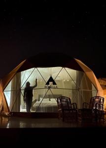 a man standing inside of a iguana tent at night at ROSELLA Wadi Rum in Disah