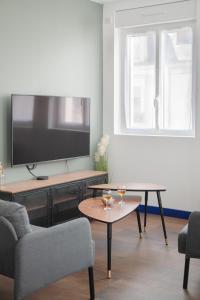 una sala de estar con TV y 2 copas de vino en una mesa en "STUDY-HOME 44600" Apt d'exception 3 Etoiles, en Saint-Nazaire