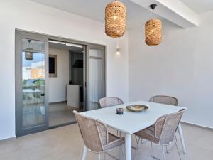 Villa Sol Alma Naousa Paros في ناوسا: غرفة طعام بيضاء مع طاولة وكراسي بيضاء