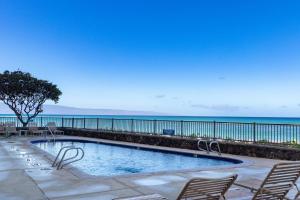a swimming pool with chairs and the ocean in the background at Tropical Hawaiian Oceanfront - indigomaui - KR210 in Kahana