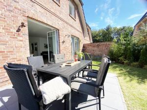 a wooden table and chairs on a patio at Haus Nordseequartier-Tating in Tating