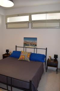 una camera da letto con un letto con lenzuola blu e due finestre di Villa Rosi a Isola delle Femmine