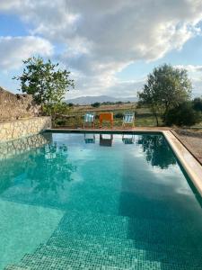 a swimming pool with two chairs and a table at Masía entre viñedos y mar in Saiforas