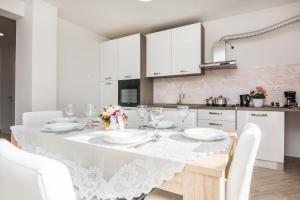 Biała kuchnia ze stołem i białymi szafkami w obiekcie Pool Apartment Bakija 2 - Happy Rentals w Pakoštane