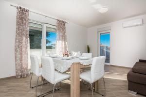 jadalnia ze stołem i białymi krzesłami w obiekcie Pool Apartment Bakija 2 - Happy Rentals w Pakoštane