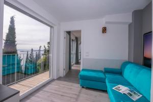 salon z niebieską kanapą i dużym oknem w obiekcie Rustichel Fantastic Lake View - Happy Rentals w mieście Toscolano Maderno
