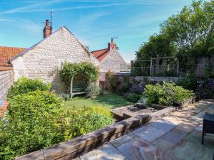 a backyard with a garden and a house at Beach Cottage in Holt