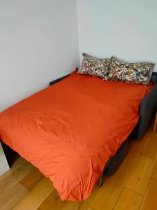 a bed with an orange comforter and a pillow at Appartement moderne à Clichy, 35 m², idéal pour 4 personnes. in Clichy