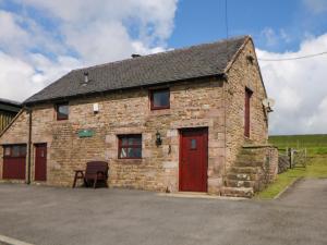 an old stone building with a red door at Downsdale Cottage in Flash