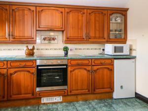 a kitchen with wooden cabinets and a white refrigerator at Downsdale Cottage in Flash