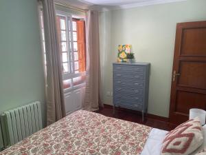 a bedroom with a bed and a dresser and a window at Figueroa Apartments in Pontevedra