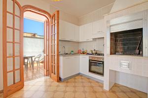 a kitchen with white cabinets and an open door at Casa Marangi 250 meters from the sea - Happy Rentals in Melendugno
