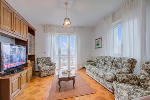 un salon avec un canapé et une télévision dans l'établissement Zio Enry Terrace Apartment Orta Lake - Happy Rentals, à Armeno