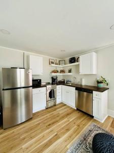 a kitchen with white cabinets and a stainless steel refrigerator at Updated, Fenced, Pet Friendly Downtown Cottage in Southern Pines