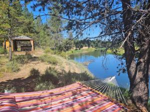 a hammock in front of a river and a gazebo at Beautiful Riverfront Near Mt Bachelor with Hot Tub in Bend