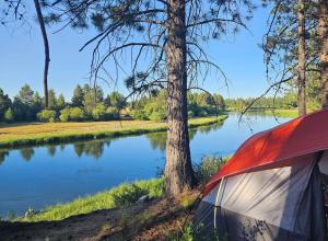 a tent pitched next to a lake and trees at Beautiful Riverfront Near Mt Bachelor with Hot Tub in Bend