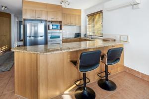 a kitchen with a large island with two bar stools at Ocean Front Views with Rooftop Terrace in Caloundra