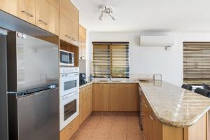 a kitchen with stainless steel appliances and wooden cabinets at Ocean Front Views with Rooftop Terrace in Caloundra
