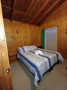 una camera da letto con un letto in una stanza di legno di Cabaña en Frutillar a Frutillar