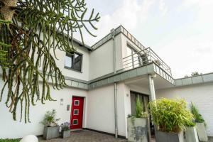a white house with a red door at Appartement 1 Engel und Co in Bad Zwischenahn
