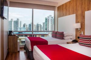 ein Hotelzimmer mit zwei Betten und einem großen Fenster in der Unterkunft Ramada by Wyndham Panama Via Argentina in Panama-Stadt